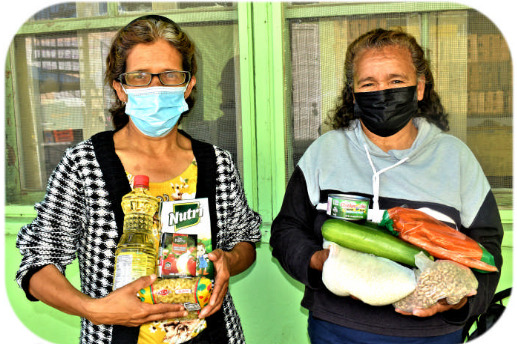 Two women holding food and blanket